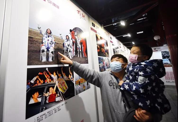 观展市民为孩子讲解2008年“神七”返回地面